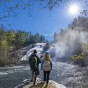 Couple relaxing by the waterfall on hiking trip.